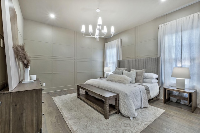 bedroom with hardwood / wood-style flooring and an inviting chandelier