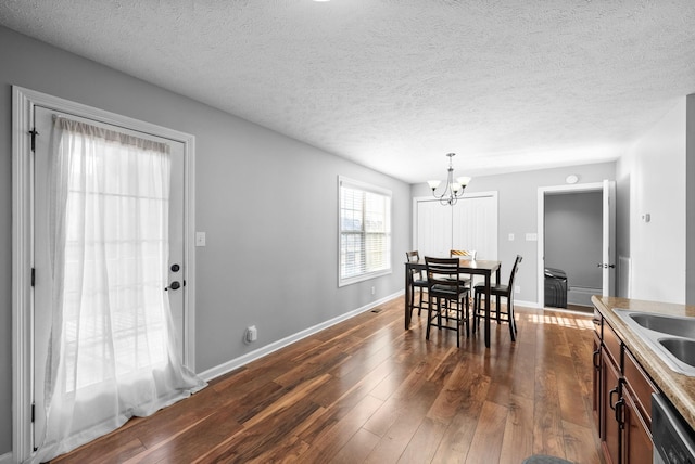 dining room featuring sink, dark hardwood / wood-style flooring, an inviting chandelier, and a textured ceiling