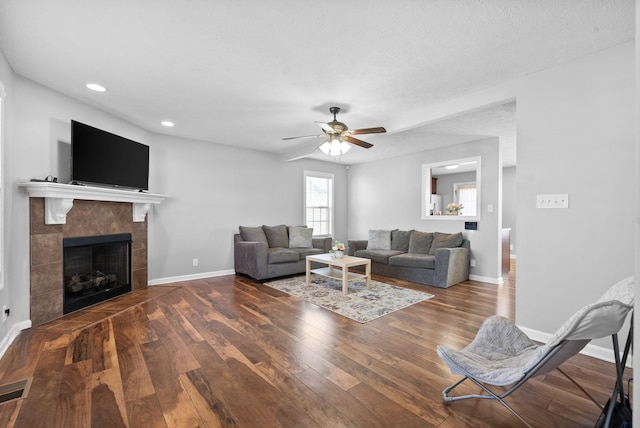 living room featuring dark hardwood / wood-style flooring, a fireplace, and ceiling fan