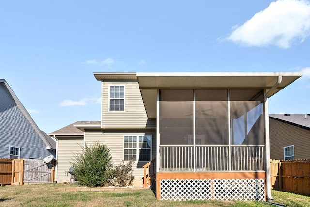 back of property featuring a sunroom and a lawn