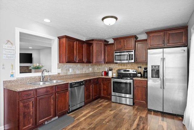 kitchen featuring appliances with stainless steel finishes, dark hardwood / wood-style floors, backsplash, and sink