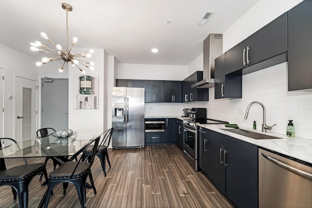 kitchen featuring sink, wall chimney exhaust hood, tasteful backsplash, a notable chandelier, and appliances with stainless steel finishes