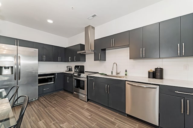 kitchen featuring sink, stainless steel appliances, wall chimney range hood, tasteful backsplash, and dark hardwood / wood-style flooring