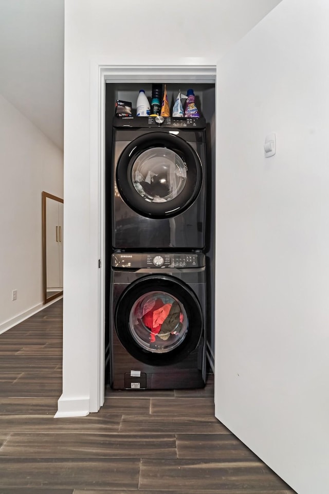 clothes washing area with dark hardwood / wood-style floors and stacked washing maching and dryer