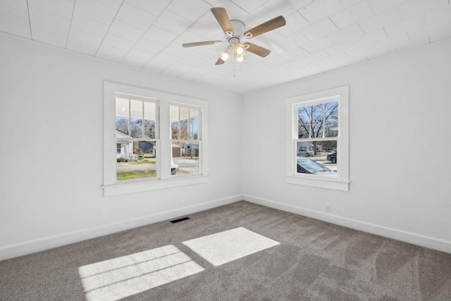 spare room with ceiling fan, plenty of natural light, and carpet