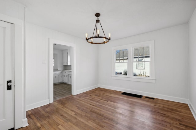 unfurnished dining area with dark hardwood / wood-style floors and a notable chandelier