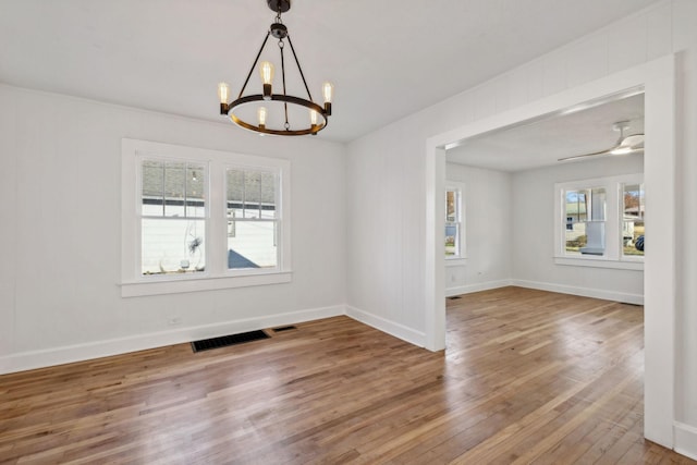 empty room featuring wood-type flooring and ceiling fan with notable chandelier