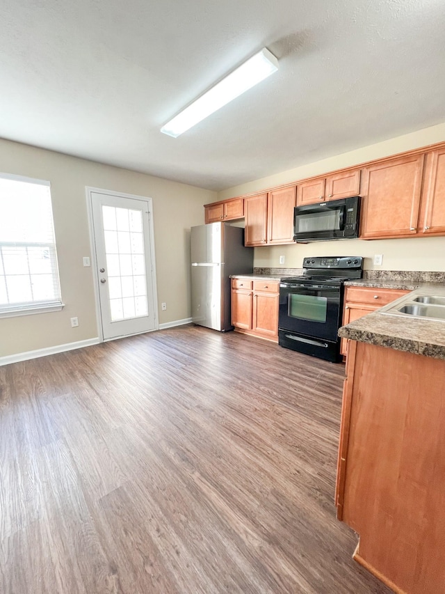 kitchen with sink, dark hardwood / wood-style flooring, and black appliances