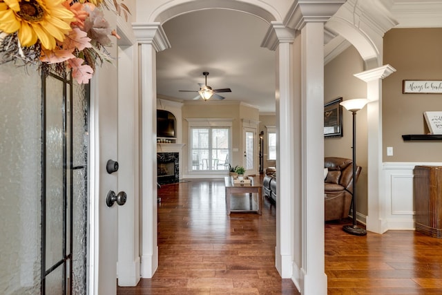 hallway with crown molding, ornate columns, and dark wood-type flooring