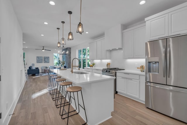 kitchen with white cabinetry, a kitchen island with sink, stainless steel appliances, and custom range hood