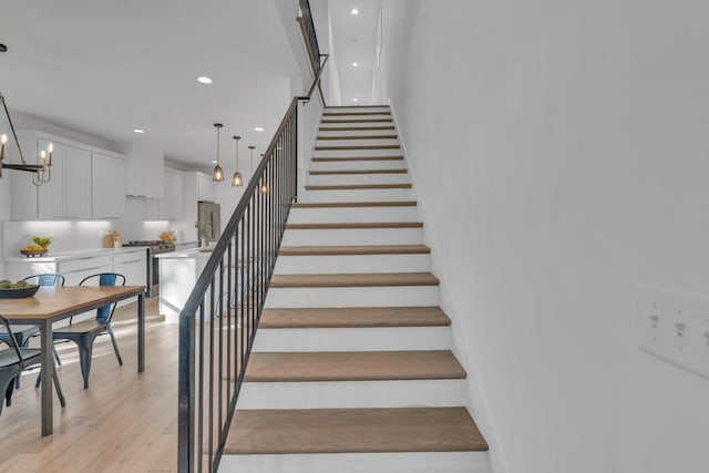 stairs with an inviting chandelier and hardwood / wood-style flooring