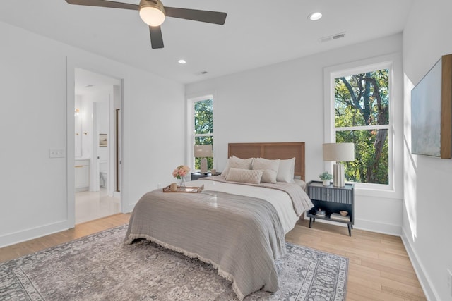 bedroom with ensuite bathroom, light hardwood / wood-style flooring, and ceiling fan