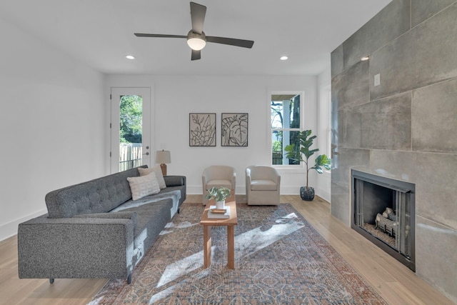 living room featuring a fireplace, ceiling fan, and light hardwood / wood-style flooring