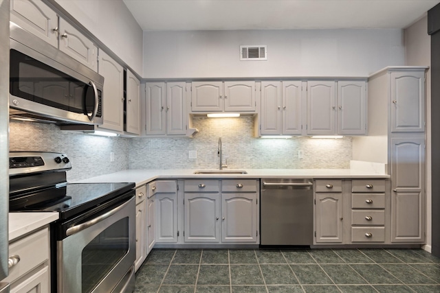 kitchen with gray cabinets, sink, stainless steel appliances, and tasteful backsplash