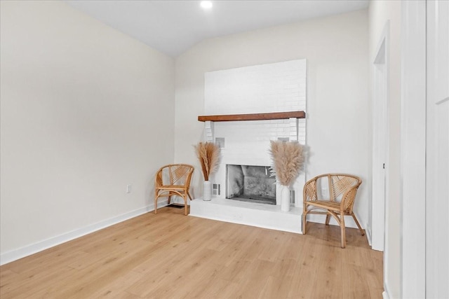 living room featuring light hardwood / wood-style floors, a fireplace, and lofted ceiling