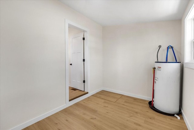 empty room with light hardwood / wood-style flooring and water heater