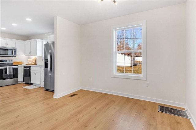 kitchen with white cabinets, light wood-type flooring, and stainless steel appliances