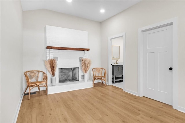 unfurnished room featuring a brick fireplace and light hardwood / wood-style floors