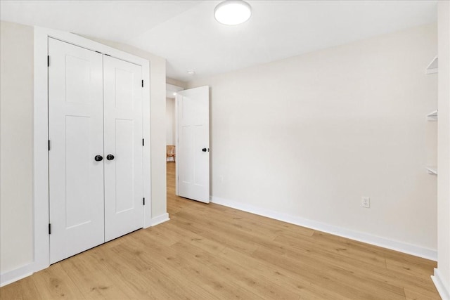 unfurnished bedroom with light hardwood / wood-style flooring, a closet, and lofted ceiling