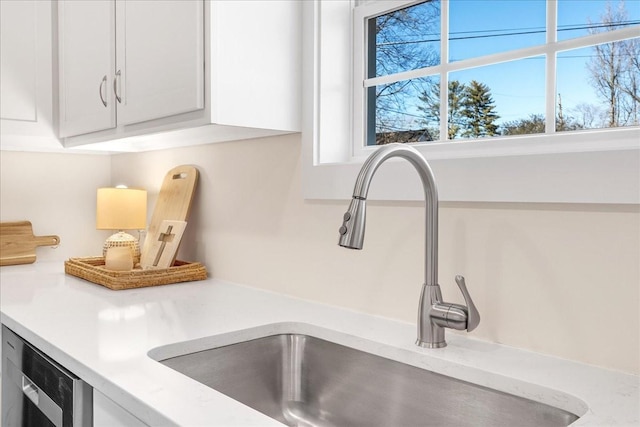 room details with sink, white cabinets, and light stone countertops