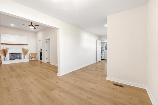 interior space with ceiling fan, light hardwood / wood-style flooring, and a brick fireplace