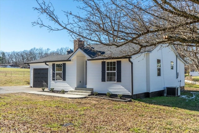 single story home with a garage, central air condition unit, and a front lawn