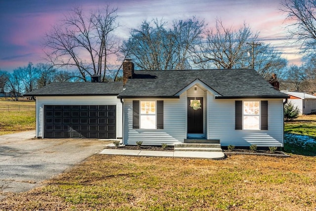 ranch-style home featuring a garage and a yard