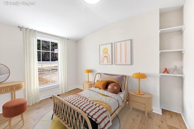 bedroom featuring multiple windows, lofted ceiling, and light wood-type flooring