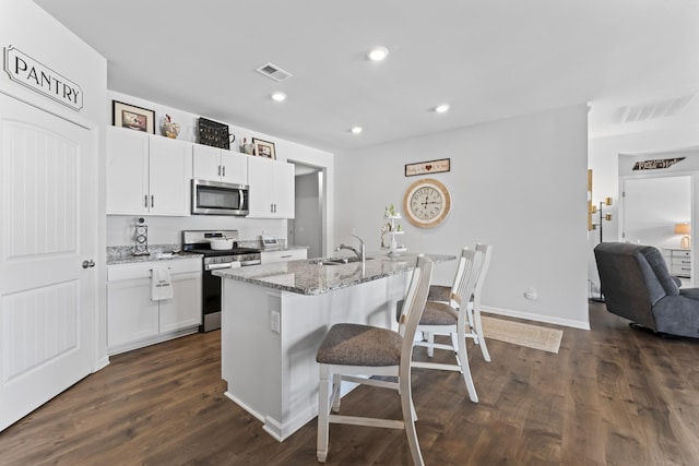 kitchen featuring appliances with stainless steel finishes, a breakfast bar, sink, dark hardwood / wood-style floors, and an island with sink