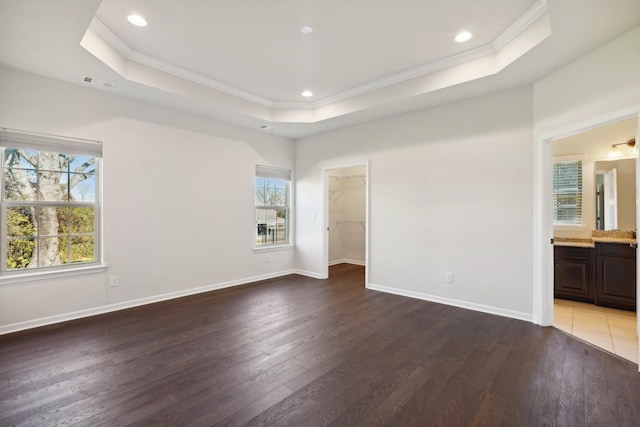 unfurnished bedroom with a walk in closet, dark hardwood / wood-style flooring, ensuite bathroom, and ornamental molding