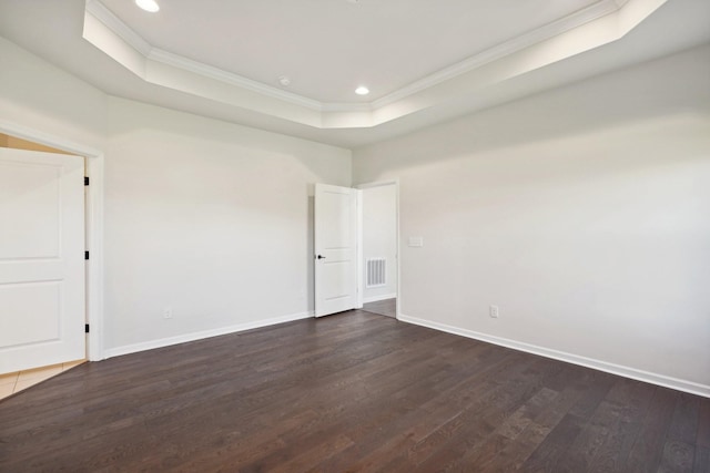 unfurnished room with dark hardwood / wood-style flooring, a tray ceiling, and ornamental molding