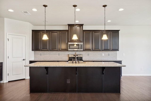 kitchen featuring a breakfast bar area, dark hardwood / wood-style flooring, stainless steel appliances, and decorative light fixtures