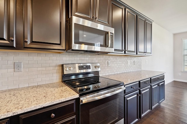 kitchen with backsplash, dark hardwood / wood-style floors, light stone countertops, dark brown cabinetry, and stainless steel appliances