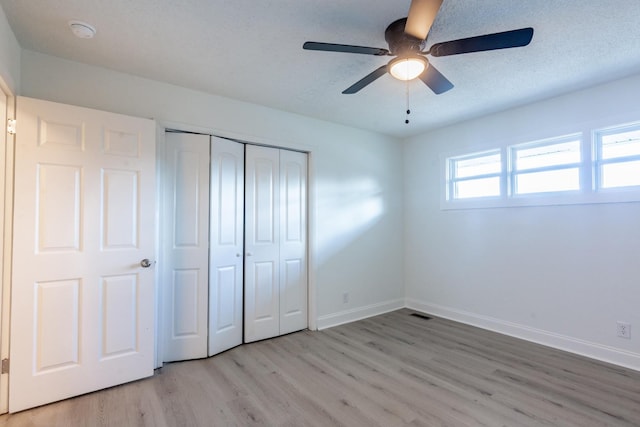 unfurnished bedroom with ceiling fan, a closet, a textured ceiling, and light wood-type flooring