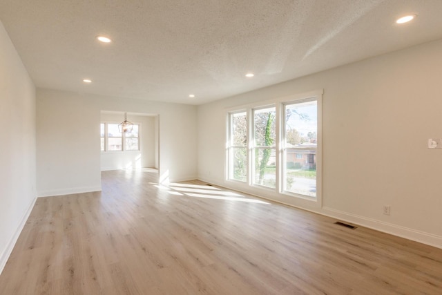 spare room with light hardwood / wood-style floors and a textured ceiling