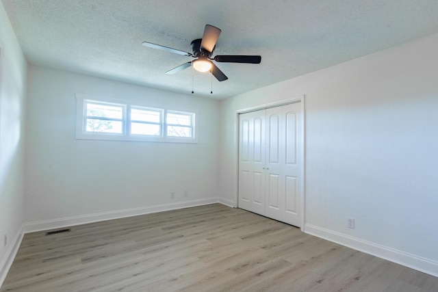 unfurnished bedroom with ceiling fan, light hardwood / wood-style floors, a textured ceiling, and a closet