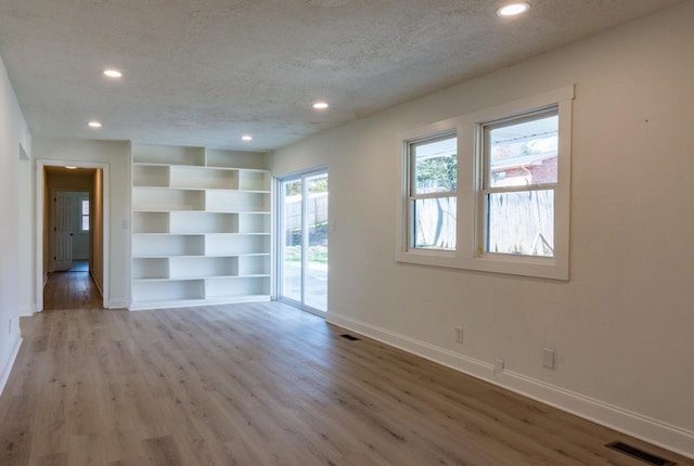 empty room with a textured ceiling and light wood-type flooring