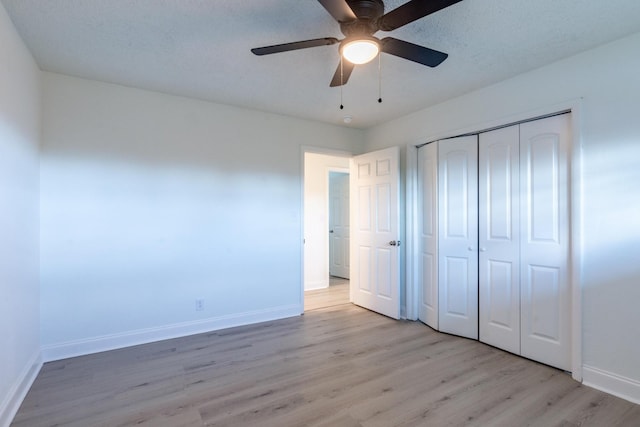 unfurnished bedroom with a textured ceiling, a closet, light hardwood / wood-style flooring, and ceiling fan