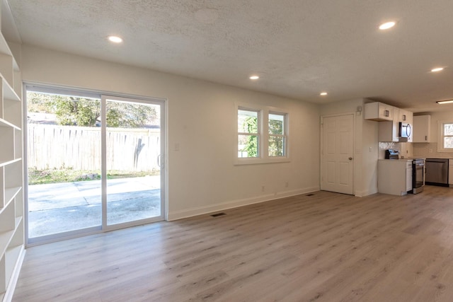 unfurnished living room featuring a textured ceiling and light hardwood / wood-style flooring