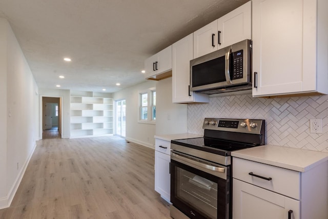 kitchen with white cabinets, decorative backsplash, light wood-type flooring, and appliances with stainless steel finishes