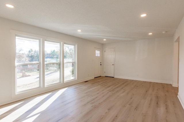 unfurnished room with light hardwood / wood-style flooring and a textured ceiling