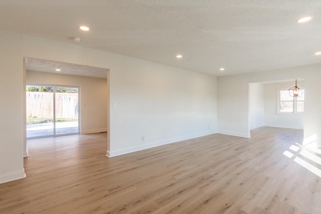 unfurnished room featuring a textured ceiling and light hardwood / wood-style flooring