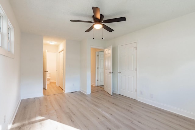 unfurnished bedroom with ceiling fan, light wood-type flooring, and ensuite bath