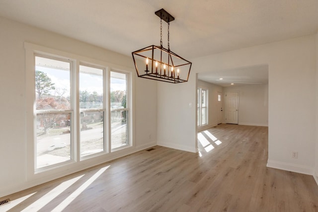 unfurnished dining area featuring light hardwood / wood-style floors and an inviting chandelier