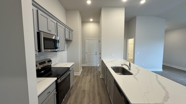 kitchen featuring light stone countertops, appliances with stainless steel finishes, dark hardwood / wood-style flooring, tasteful backsplash, and sink