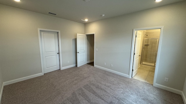 unfurnished bedroom with ensuite bathroom and light carpet