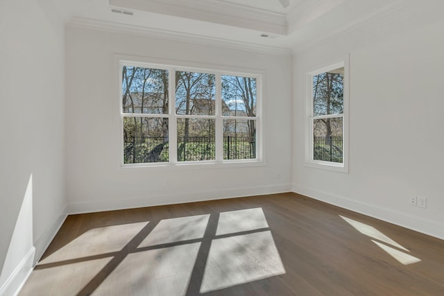 spare room featuring ornamental molding, visible vents, baseboards, and wood finished floors