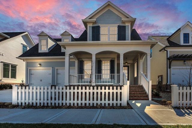 view of front of home featuring covered porch, a fenced front yard, and an attached garage