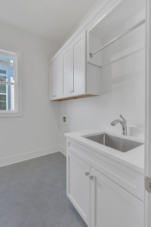 washroom featuring hookup for a washing machine, dark tile patterned flooring, a sink, baseboards, and cabinet space