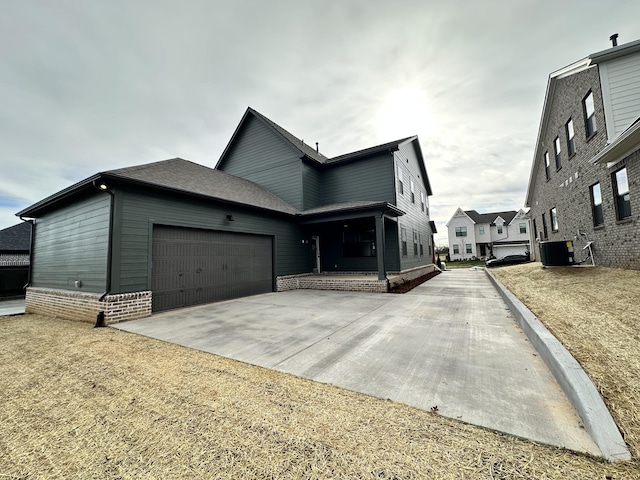 view of front of house featuring a garage, cooling unit, concrete driveway, and roof with shingles